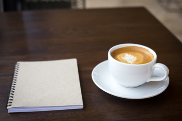 Coffee cup and notebook on grunge wooden background.
