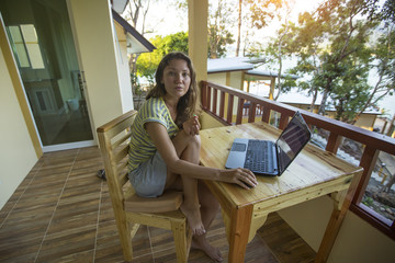 Worried girl is a freelancer with a laptop in the condo terrace near the sea.
