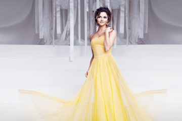 smiling woman in yellow evening dress and with beautiful hairstyle, party