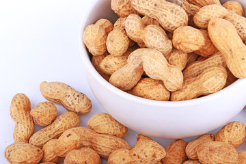 Monkey nuts, peanuts or groundnuts in shells, isolated on a white background in cup