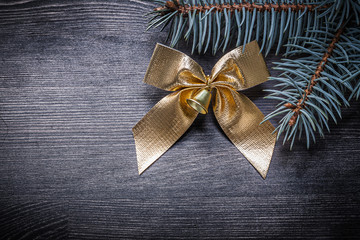 Golden bow fir tree branch on wooden board holiday concept