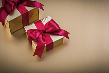 Wrapped giftboxes with tied bows on golden surface holidays conc