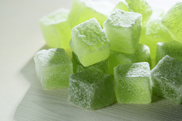 Natural green marmalade cubes, closeup on the white wood