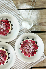Sweet cakes with raspberries on light wooden background