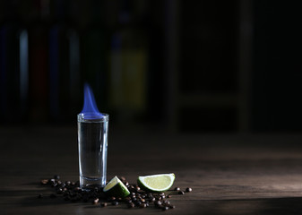 Burning cocktail with lime and coffee beans on table in a bar
