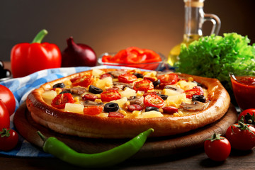 Delicious pizza with vegetables and meat on brown background