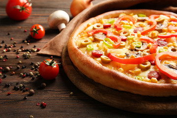 Delicious pizza with vegetables on wooden table