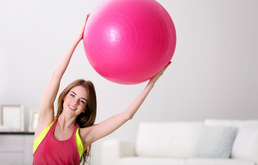 Fototapeta premium Beautiful young girl doing exercises with fit ball at home