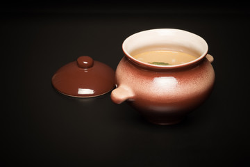 Rice soup in a clay pot on a black table or background. Toned
