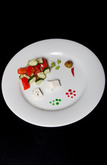 White plate with fresh salad on a black table or background