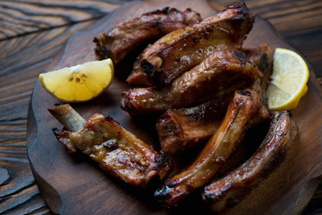 Closeup of baked pork ribs served with lemon, selective focus