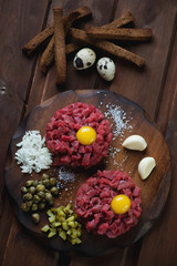 Top view of two beef tartars on a wooden chopping board