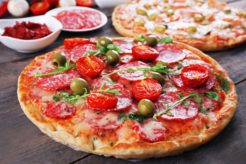 Delicious tasty pizzas with ingredients on table, closeup