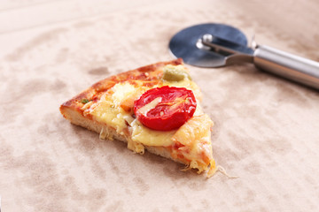Slice of delicious pizza in cardboard with cutter, closeup