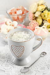 Mug of hot chocolate with marshmallows, on light wooden background