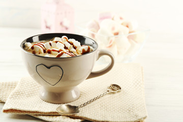 Mug of hot chocolate with marshmallows, on light wooden background