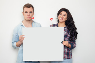 Cheerful boyfriend and girlfriend are presenting a billboard