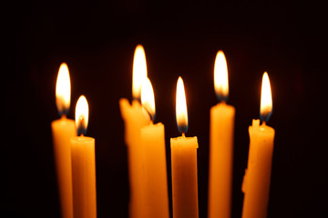 Many burning candles on black