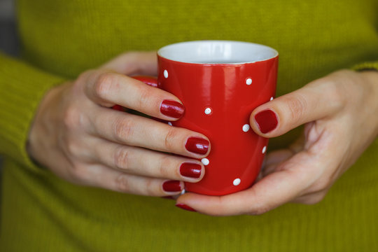 Woman hands holding a cozy red mug