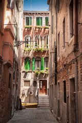 Narrow street in Venice leading to canal bridge