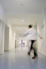 Motion blurred doctor rushes down hospital corridor