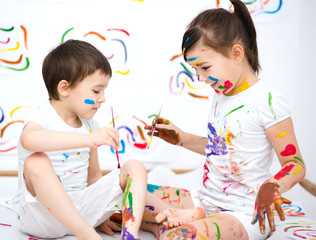 Cute boy and girl playing with paints