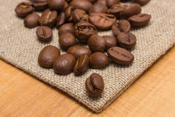 Heap of coffee beans on jute canvas on table