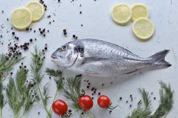 Raw dorado  with dill , lemon, tomatoes on  wooden background 