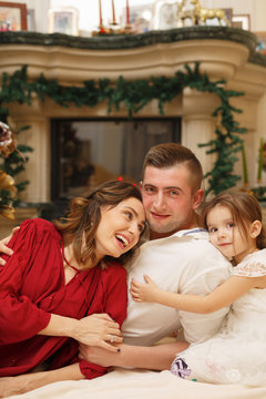 Cute young laughing family at home near the christmas tree in decorated room
