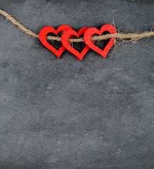 Vintage chalkboard with three red heart shape symbols on rope,  retro filter applied, love concept