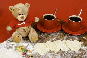 Hearts of dough, teddy bear and red cup of coffee.