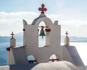 A bell tower at a Greek Orthodox church in Oia town on the island of Santorini, Greece with the...