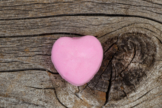Happy Valentines day with single pink heart shaped candy on wood