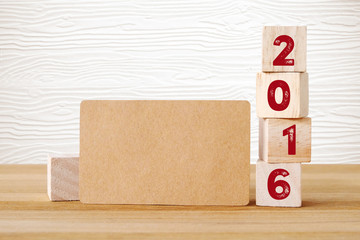 Blank recycle paper card and wooden cubes with 2016 on table and