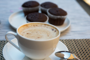 Cup of coffee and chocolate muffins background
