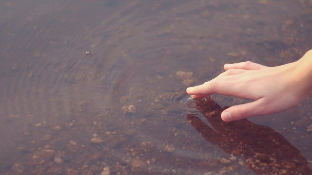 Girl hand caresses the lake water
