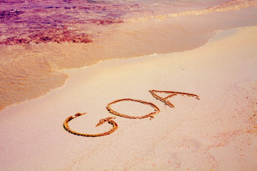 Text GOA on the sand on the beach