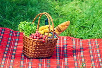 Picnic basket with fruits on the blanket