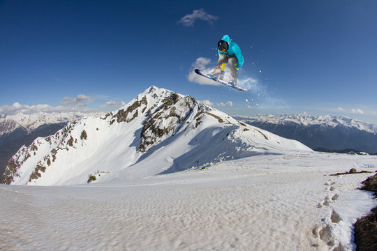 Flying snowboarder on mountains. Extreme sport.