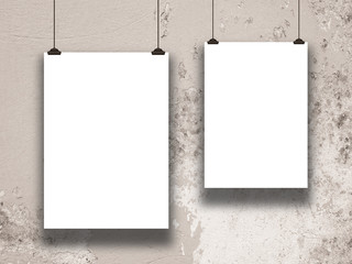 Close-up of two hanged paper sheet frames with clips on weathered concrete wall background