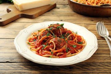 Pasta italiana con polpette di carne su sfondo legno rustico