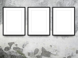 Close-up of three black picture frames on stained concrete wall background