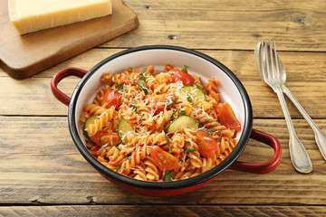  Pasta italiana con zucchini e pomodoro su sfondo legno rustico