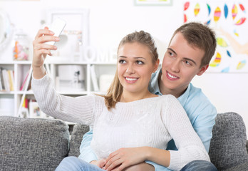 Young hugging couple on the couch taking a selfie
