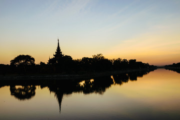 Silhouette scene of moat and Fort of Mandalay palace at sunset