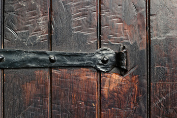 Old rustic wooden door with iron hinge