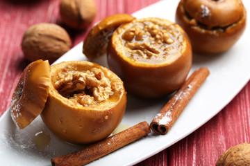 Baked apples on plate on red wooden table