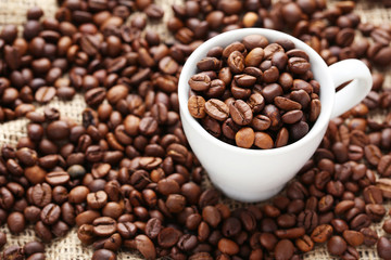 Coffee beans in cup on a sack, close up