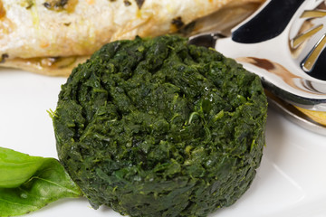 Grilled sea bass with spinach garnish.