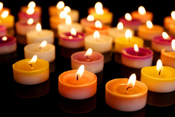 Fototapeta na wymiar Many burning small candles on dark background